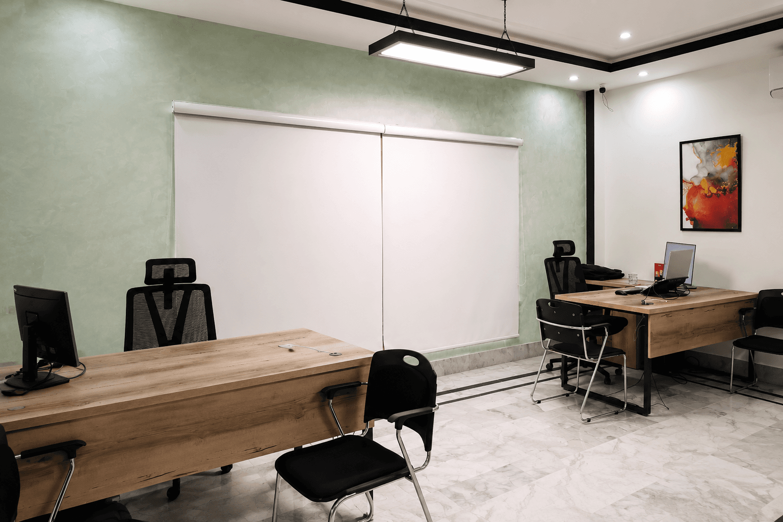 Private office with three desks, framed artwork and a blue patterned rug