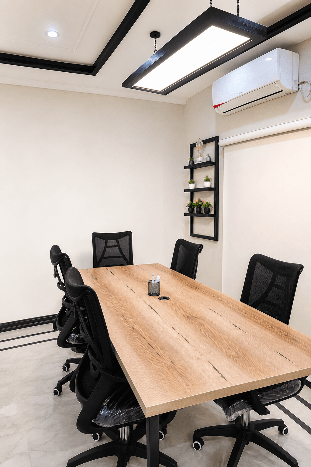 The Worklane meeting room, with a wooden table, mesh chairs and a shelf of plants