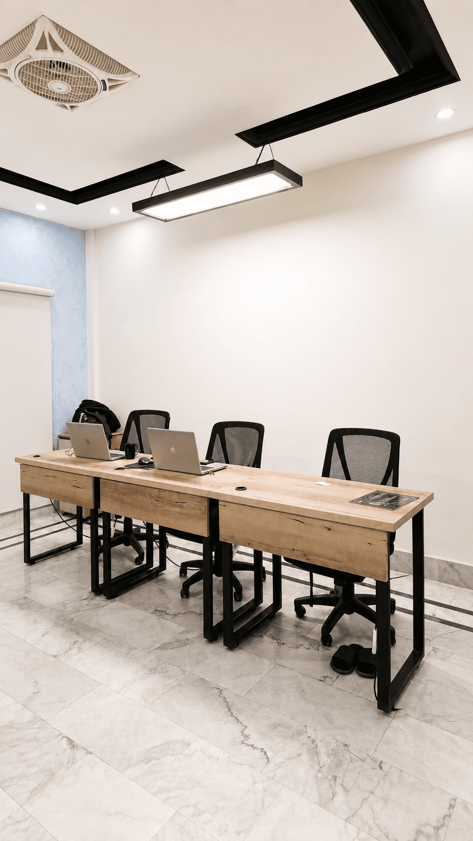 Private office at The Worklane with three desks, laptops and a blue feature wall